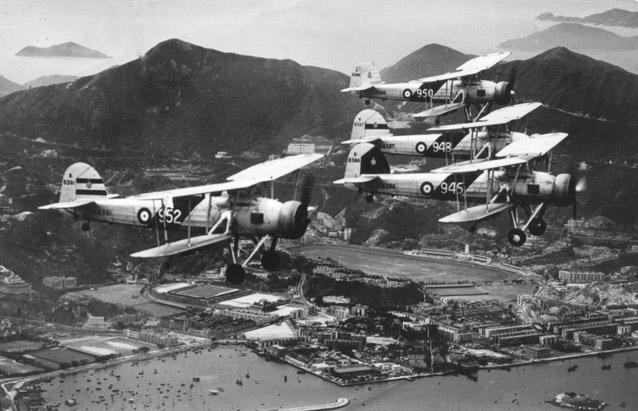 824 Squadron Swordfish from HMS Eagle on Coronation Flypast over Hong Kong (Happy Valley racecourse in background).  Pilot of 945 with black flight leader's marking on tail is Sqn Ldr AB Woodhall and crew is L/Tel Faulkner and Lt Gardner.  Photo taken  0825, May 12, 1937. 